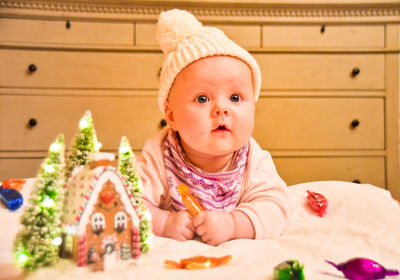Thoughtful baby girl with christmas decoration on bed at home
