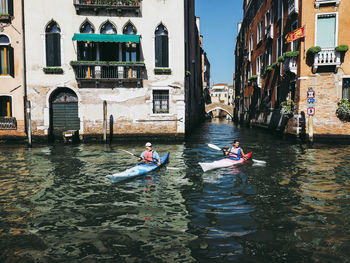 Boats in canal amidst buildings in city