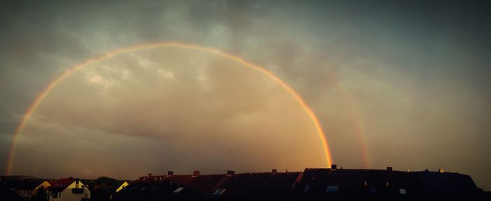Low angle view of rainbow over buildings against sky