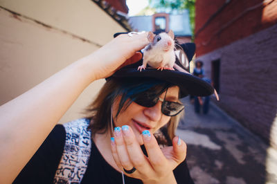 A girl with colored hair holds a rat on the visor of her cap. pets are teenager's friends. 