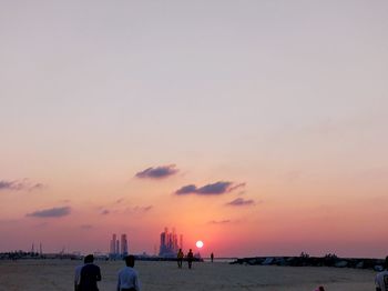 People on beach against sky during sunset