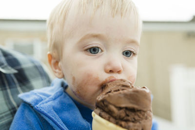 Close-up of son eating ice cream while sitting with father