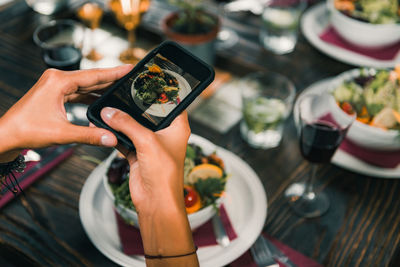 Cropped hand of woman photographing food on smart phone