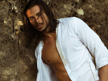 Portrait of young man standing against rock