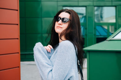 Portrait of beautiful woman standing against brick wall