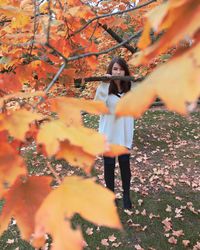 Midsection of woman standing by tree during autumn