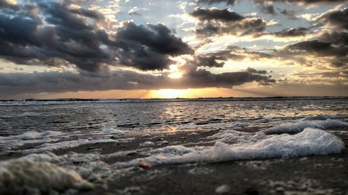 Scenic view of sea against dramatic sky during sunset