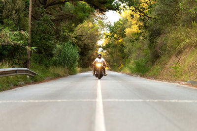 Young man on a vintage motorcycle on a mountain road at sunset