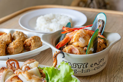 Close-up of curry streamed seafood in a cup on wooden table.