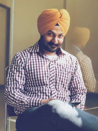 Portrait of man wearing turban sitting at home