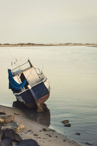 Boats moored in calm sea against clear sky