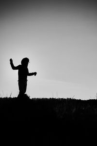 Silhouette man standing on field against clear sky