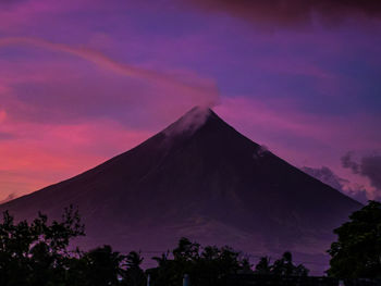 Silhouette of trees against cloudy sky at sunset