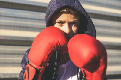 Portrait of boy in boxing glove standing outdoors