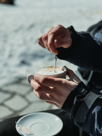 Cropped hand of man holding coffee on mountain in winter