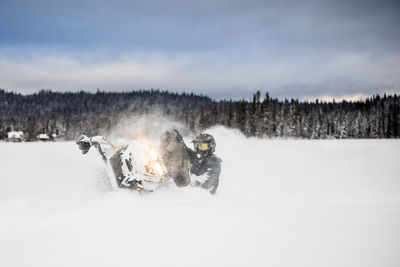 Confident and aggressive rider operates snowmobile in deep snow.