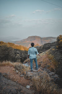 Rear view full length of man standing on mountain against sky