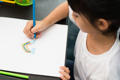 Close-up of cute girl holding paper with text on table