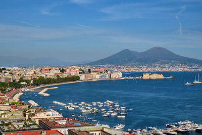 Aerial view of city by sea against sky