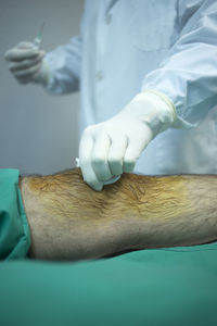 Midsection of doctor examining patient knee in hospital