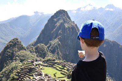 Rear view of boy looking at mountains against sky