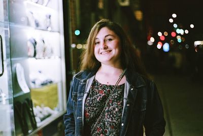 Portrait of smiling young woman standing at night