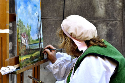 Rear view of woman wearing hat against wall