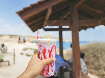 Close-up of hand holding ice cream cone at beach