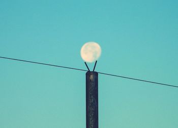 Low angle view of electricity pylon against clear blue sky
