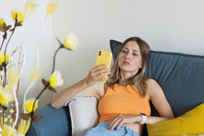Woman using mobile phone while sitting on sofa at home