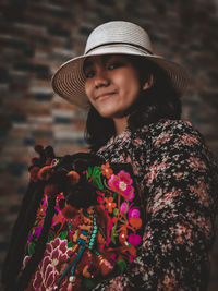 A young girl wearing floral patterned outfit and hat, carrying a colorful floral bag 