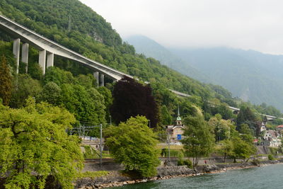 Bridge over river amidst trees and mountains