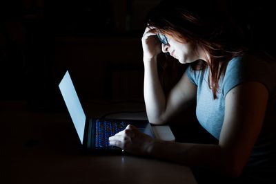 Frustrated woman working on laptop in darkroom