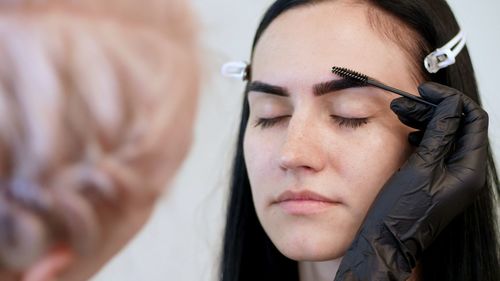 Beauty saloon. close-up, a beautician in black rubber gloves, gently combs the eyebrows