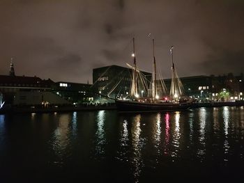 Illuminated harbor by river against sky at night