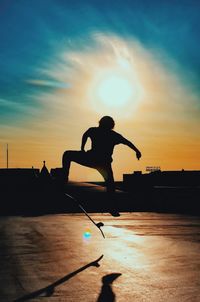 Silhouette man skateboarding at park against sky during sunset