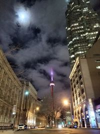 Low angle view of illuminated buildings against cloudy sky