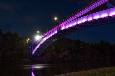 Illuminated bridge over river at night