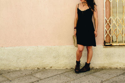 Full length of woman standing against wall