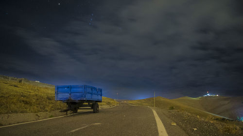 Vehicle on road against cloudy sky at night