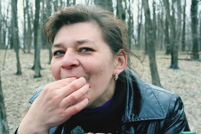 Close-up of woman with finger in mouth at forest