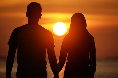 Rear view of silhouette of couple against sunset