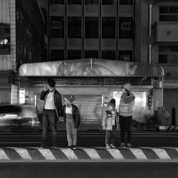 Rear view of people standing at railroad station