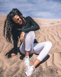 Full length of young woman sitting on sand