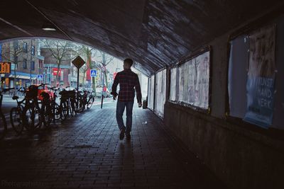 Rear view of man walking on bicycle in city