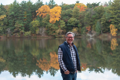 Portrait of man standing by lake during autumn