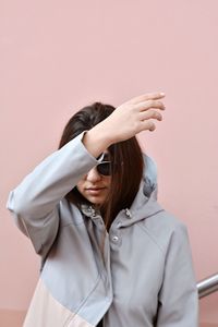 Young woman gesturing against wall