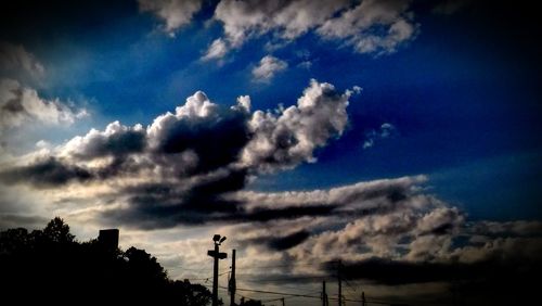 Low angle view of electricity pylon against cloudy sky