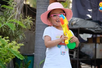 Portrait of smiling girl holding squirt gun while standing outdoors