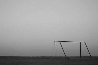 Wind turbines on field by sea against clear sky